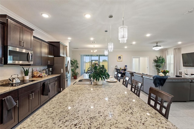 kitchen featuring crown molding, appliances with stainless steel finishes, open floor plan, a sink, and dark brown cabinets