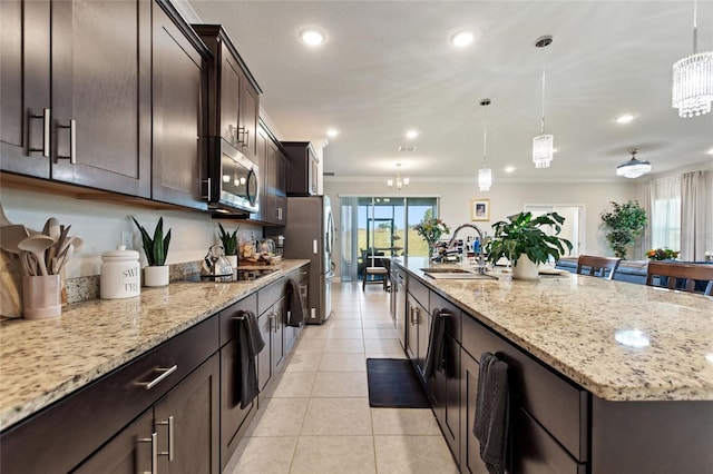 kitchen featuring light tile patterned floors, a sink, appliances with stainless steel finishes, a large island with sink, and crown molding