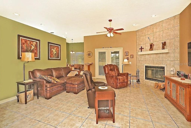 living room with light tile patterned floors, a tiled fireplace, and a ceiling fan