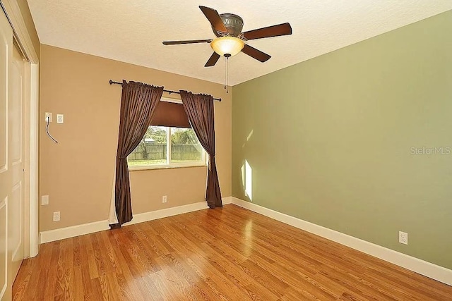 spare room with a textured ceiling, a ceiling fan, baseboards, and wood finished floors