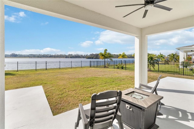 view of yard featuring a water view, an outdoor fire pit, ceiling fan, and a patio