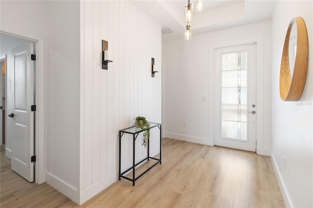 entryway with light hardwood / wood-style flooring, a raised ceiling, and a healthy amount of sunlight