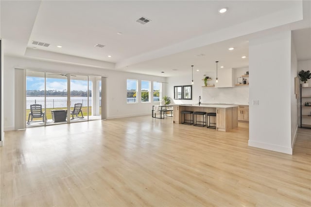 living room with a water view, light hardwood / wood-style flooring, and sink