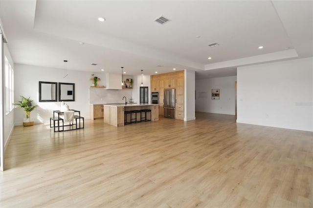 living room with light hardwood / wood-style floors, a tray ceiling, and sink