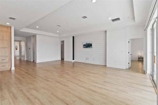 unfurnished living room with light hardwood / wood-style floors and a tray ceiling