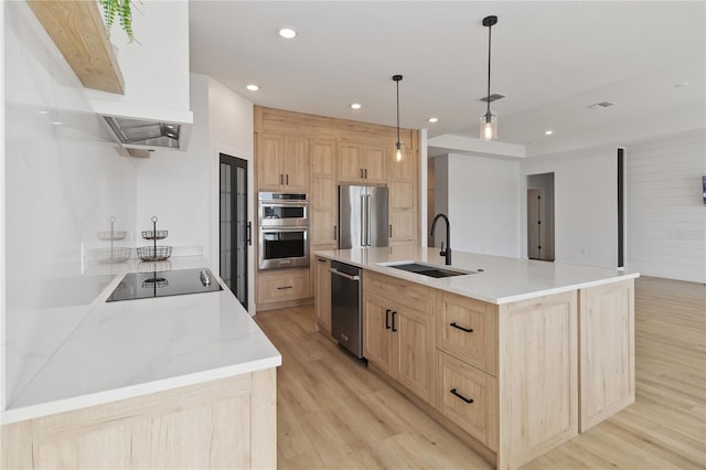 kitchen with decorative light fixtures, sink, appliances with stainless steel finishes, a large island, and light brown cabinetry