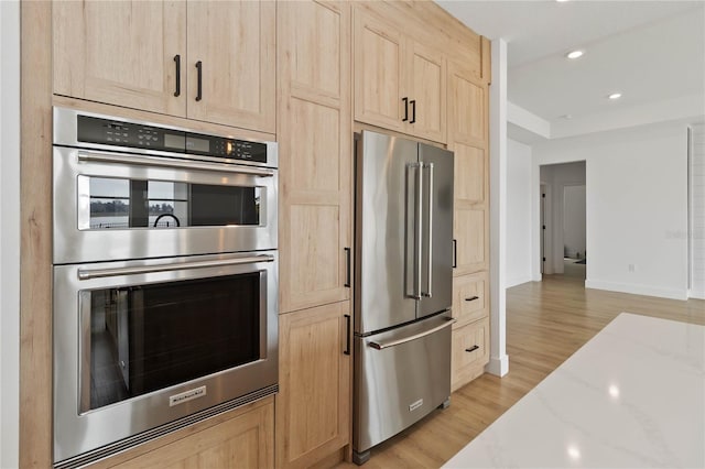 kitchen featuring light brown cabinets, stainless steel appliances, light hardwood / wood-style floors, and light stone counters