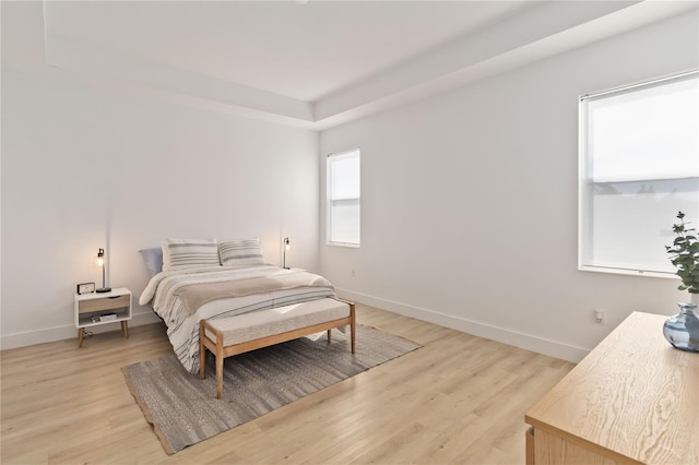 bedroom featuring a tray ceiling and light wood-type flooring