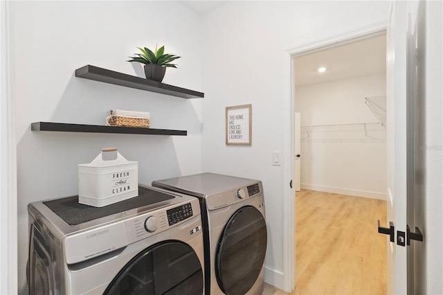 clothes washing area featuring washer and clothes dryer and light wood-type flooring