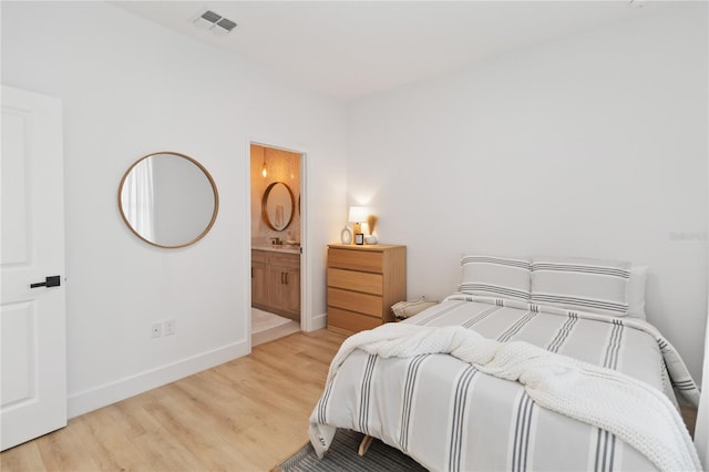 bedroom with ensuite bath and light wood-type flooring