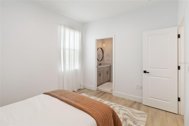 bedroom with sink, light hardwood / wood-style floors, and ensuite bath