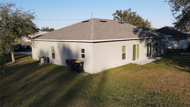 back of house with central AC unit and a yard