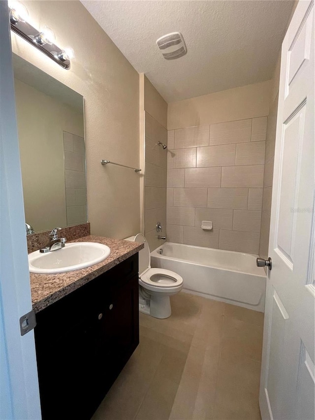 full bathroom with toilet, tiled shower / bath, vanity, and a textured ceiling