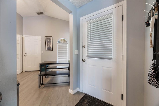 foyer featuring vaulted ceiling, a textured ceiling, and light hardwood / wood-style flooring