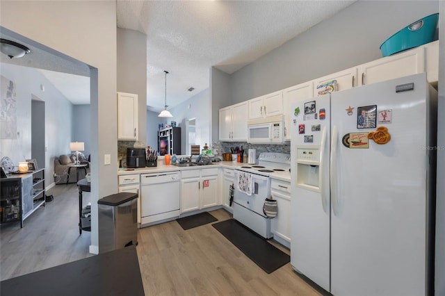 kitchen featuring hanging light fixtures, white cabinets, backsplash, and white appliances