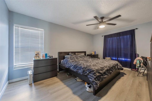 bedroom with light wood-type flooring, ceiling fan, and a textured ceiling