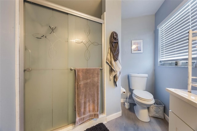 bathroom with hardwood / wood-style flooring, toilet, a shower with door, and vanity