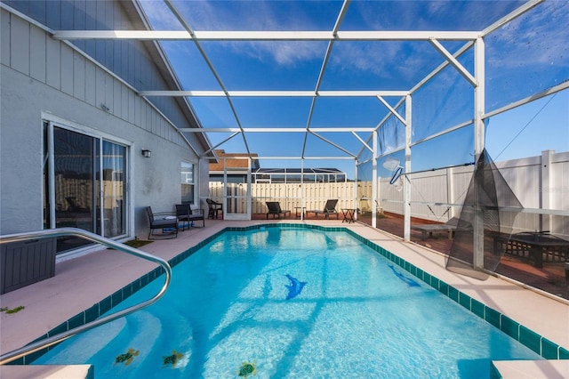 view of pool with glass enclosure and a patio area