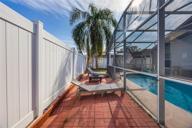 view of pool with glass enclosure and a patio area