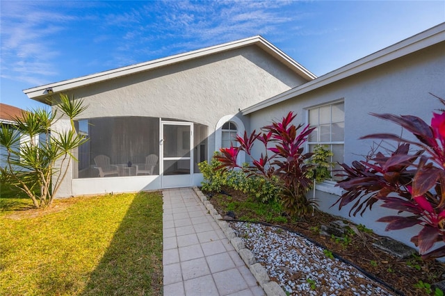 back of property with a yard and a sunroom