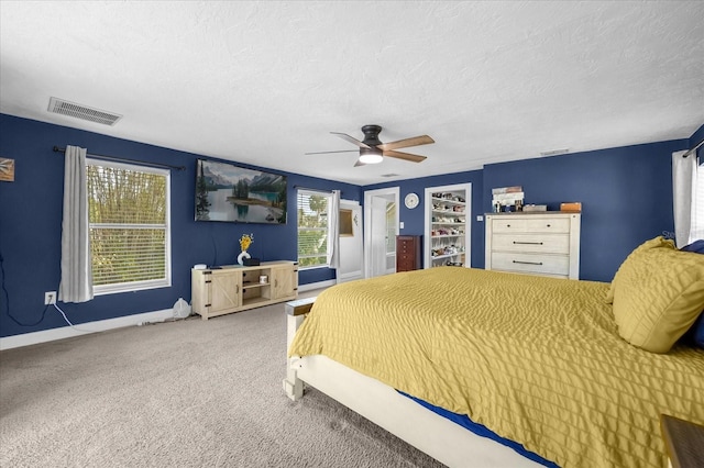 bedroom featuring visible vents, baseboards, a ceiling fan, carpet, and a textured ceiling