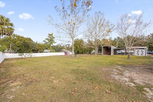 view of yard featuring a carport, fence, and an outdoor structure