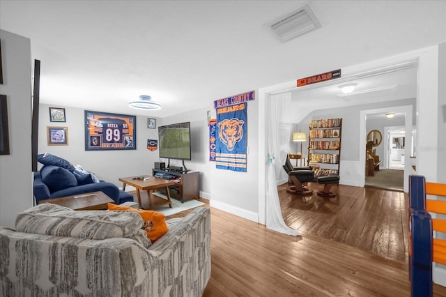 living area featuring hardwood / wood-style flooring, visible vents, and baseboards