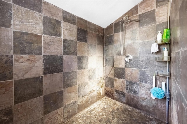 full bathroom featuring vaulted ceiling and a tile shower