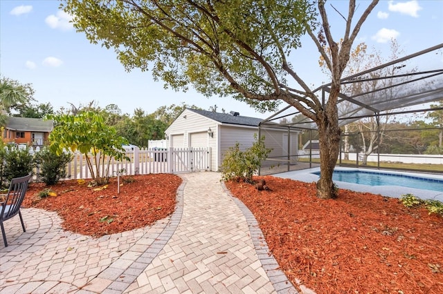 view of yard with a fenced in pool, a patio, glass enclosure, fence, and an outdoor structure