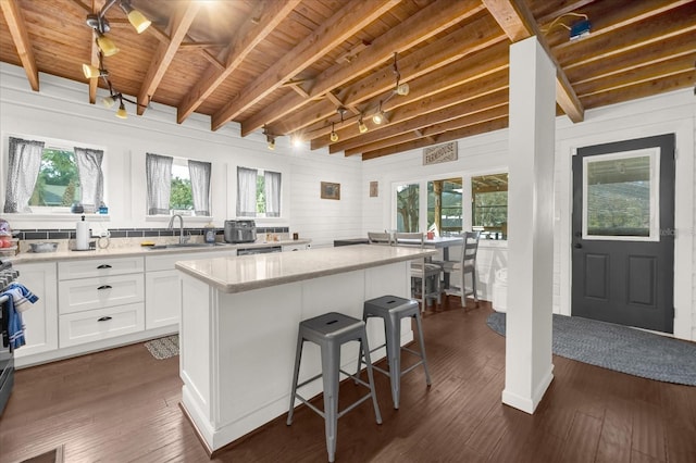 kitchen featuring dark wood finished floors, wooden ceiling, a kitchen island, a kitchen breakfast bar, and white cabinetry