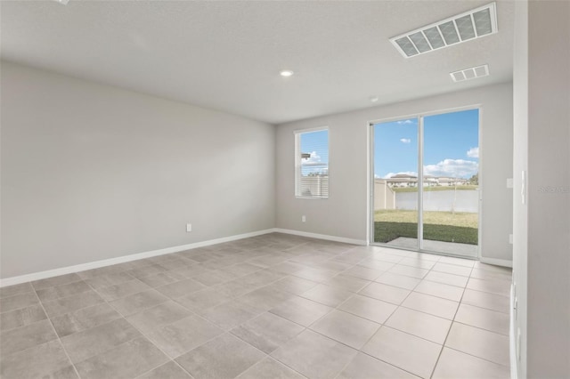 empty room with visible vents, baseboards, and light tile patterned floors