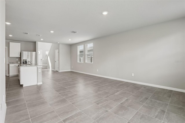 unfurnished living room featuring light tile patterned flooring, baseboards, visible vents, and recessed lighting