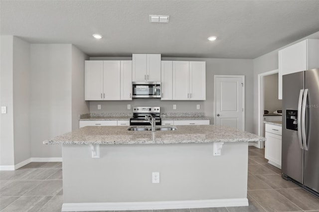 kitchen featuring visible vents, appliances with stainless steel finishes, light tile patterned flooring, a sink, and white cabinetry