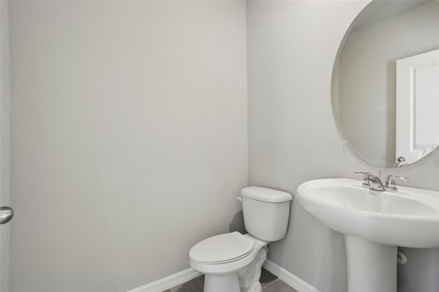 bathroom featuring baseboards, a sink, and toilet