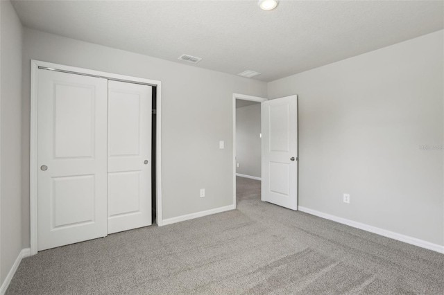 unfurnished bedroom with carpet floors, a closet, visible vents, and baseboards