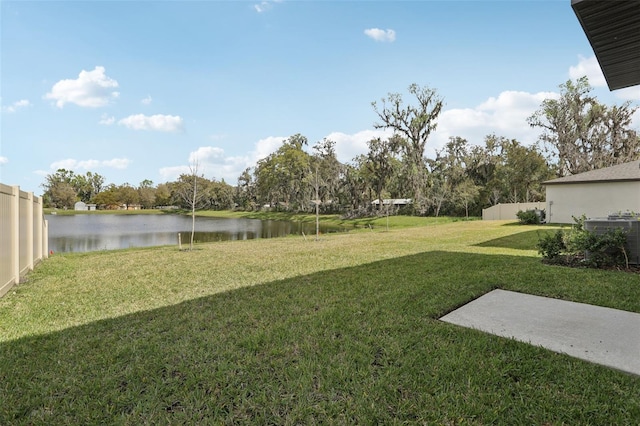 view of yard with a water view, fence, and central AC