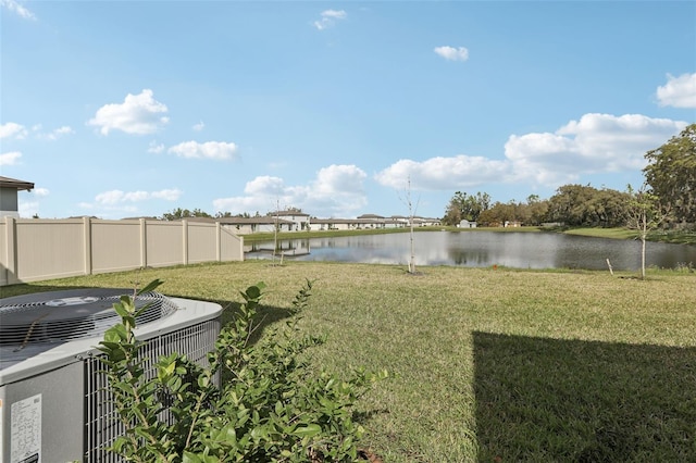 view of yard featuring a water view, fence, and central air condition unit