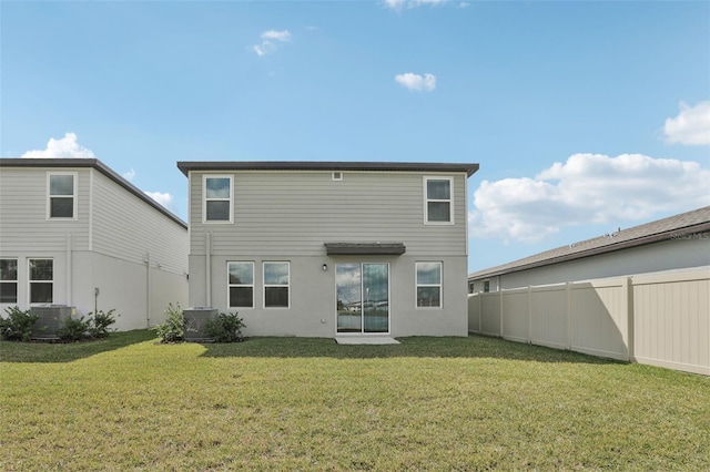 rear view of property with a lawn, cooling unit, and fence