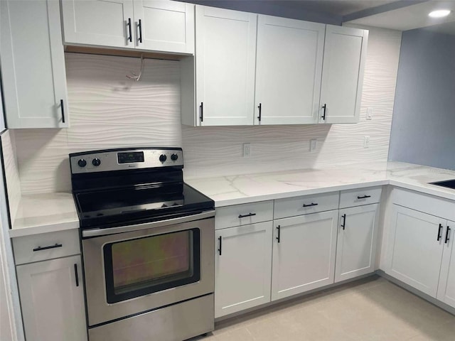 kitchen featuring stainless steel range with electric stovetop, backsplash, white cabinets, and light stone counters