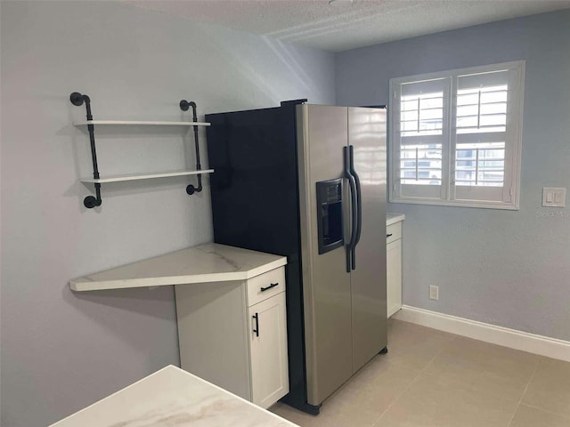 kitchen featuring stainless steel refrigerator with ice dispenser, white cabinetry, and a textured ceiling