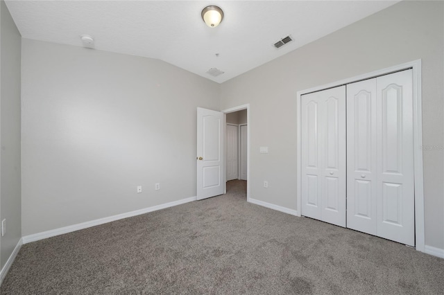 unfurnished bedroom featuring lofted ceiling, carpet floors, and a closet