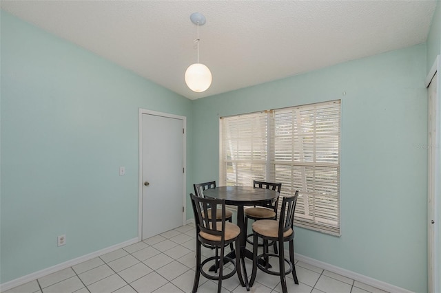 dining space featuring a textured ceiling, light tile patterned floors, and lofted ceiling