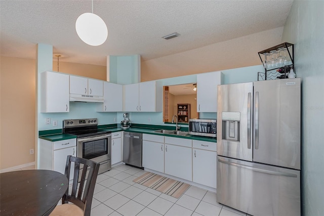 kitchen featuring lofted ceiling, sink, light tile patterned flooring, appliances with stainless steel finishes, and white cabinets