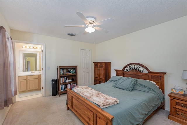 carpeted bedroom featuring ceiling fan, a textured ceiling, a closet, and ensuite bath