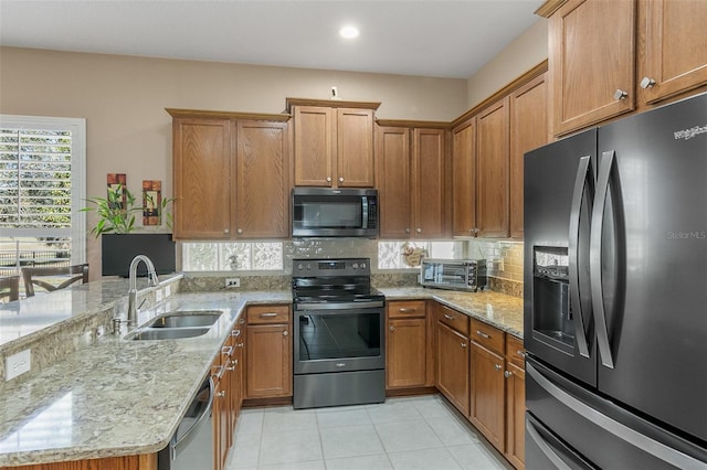 kitchen with tasteful backsplash, stainless steel appliances, light stone countertops, and sink