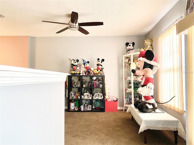 recreation room featuring ceiling fan, a textured ceiling, and carpet flooring