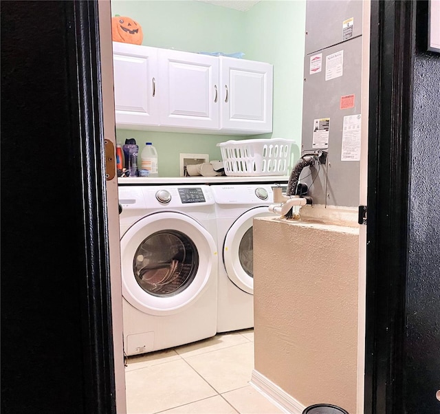 laundry area featuring washing machine and dryer, light tile patterned floors, and cabinets