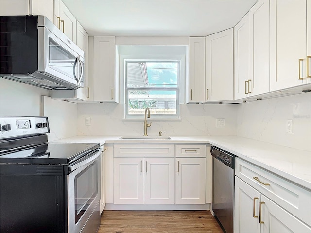 930 Lewis Dr, Daytona Beach, FL 32117 - kitchen with stainless steel appliances, light wood finished floors, white cabinets, and a sink