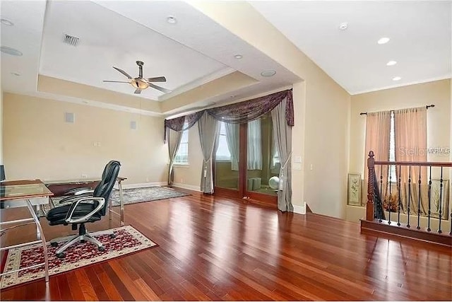 office space featuring ceiling fan, hardwood / wood-style floors, and a tray ceiling