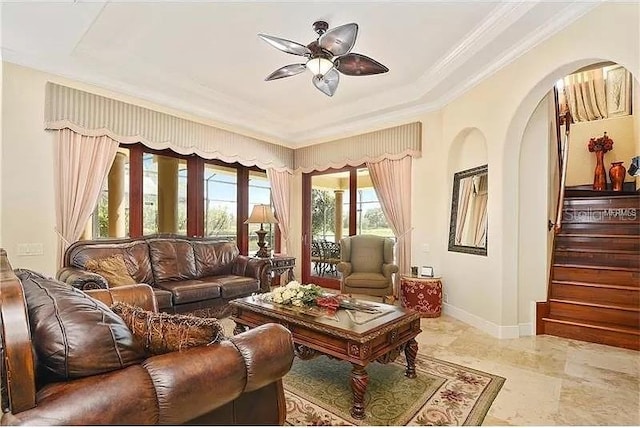 living room featuring ceiling fan, ornamental molding, and a tray ceiling